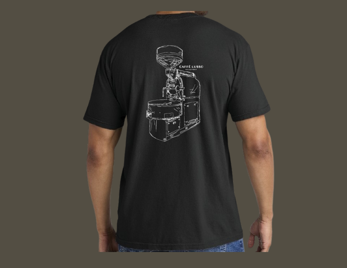 A person wearing a black, heavy weight ring spun cotton tee with a hand sketched drawing of a coffee roasting machine on the back.