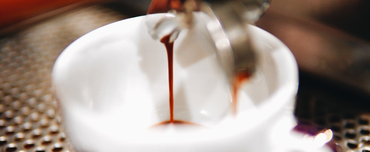 espresso dripping into a demitasse cup- close up