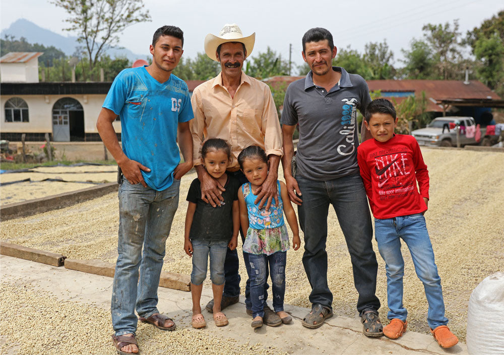 Guatemala armer and his family in front of drying coffee